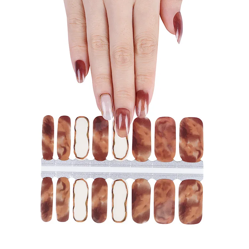Hand with brown nails above marbled gold-edged nail stickers