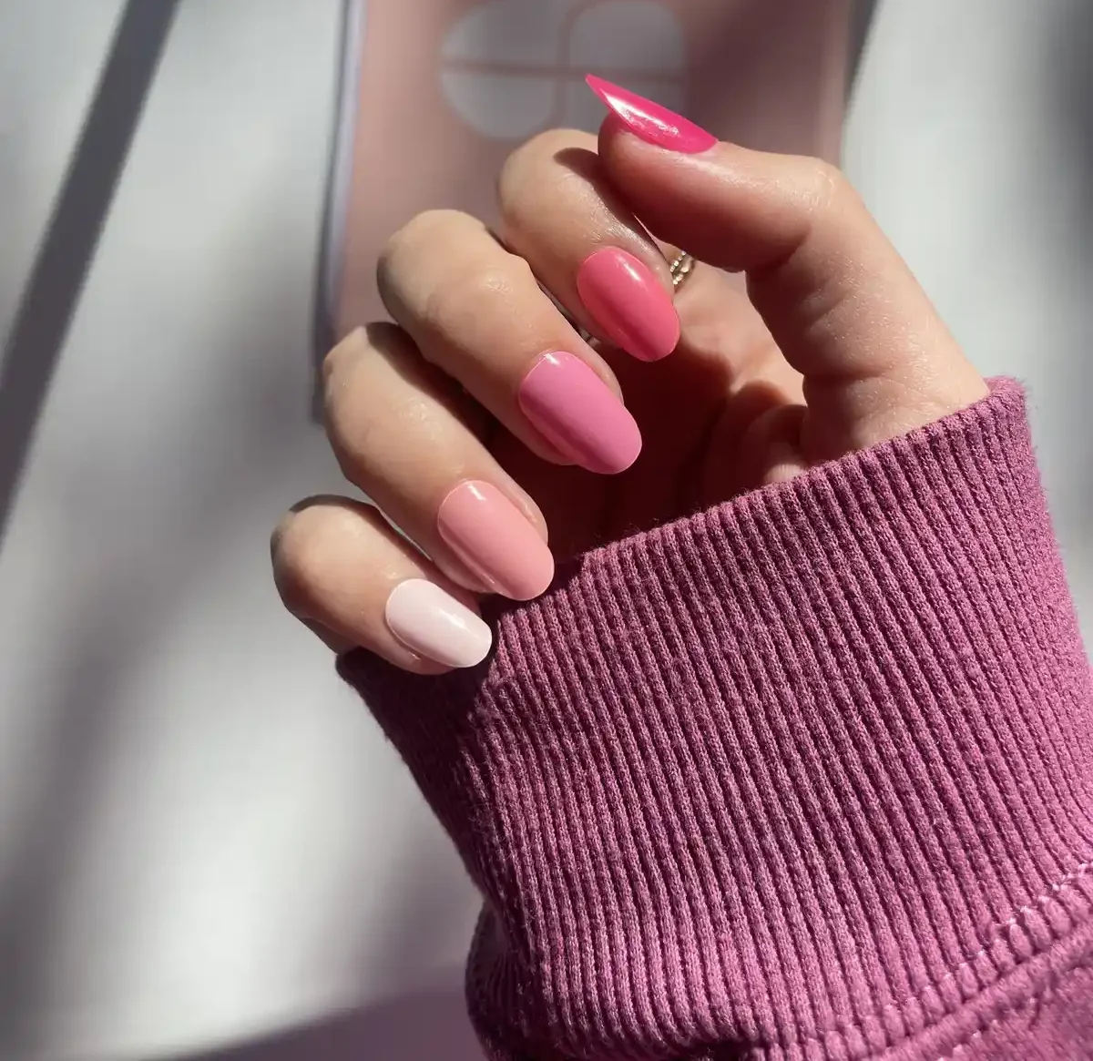 Hand with pink gradient nails and purple sleeve