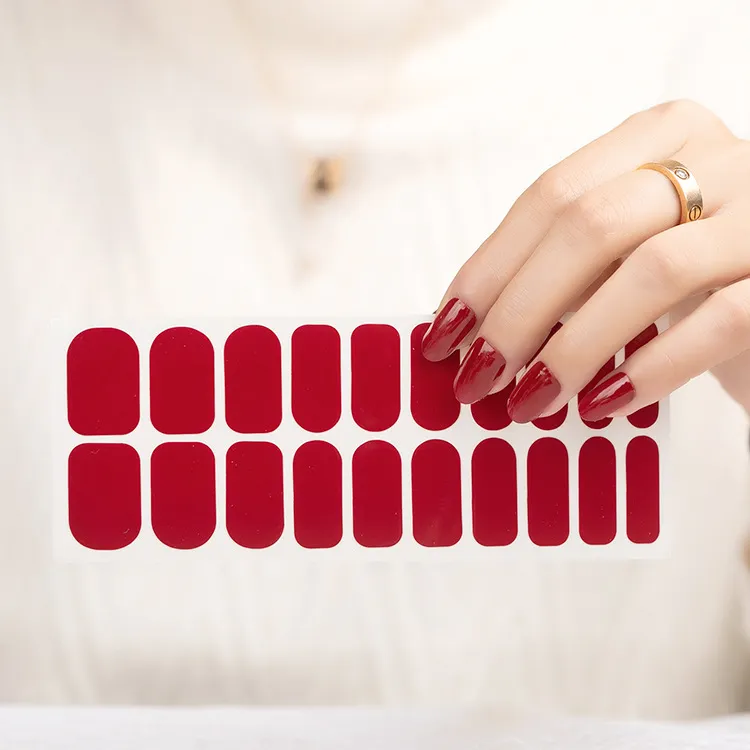 Hand with red nails holding red oval nail stickers sheet