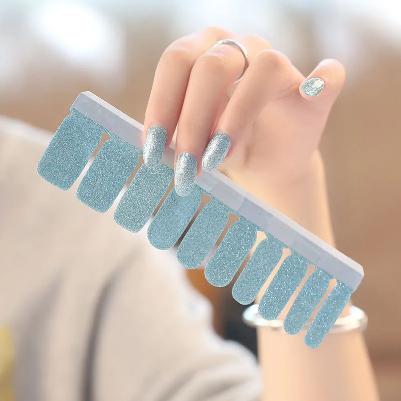 Silver glitter nails holding blue press-on nails