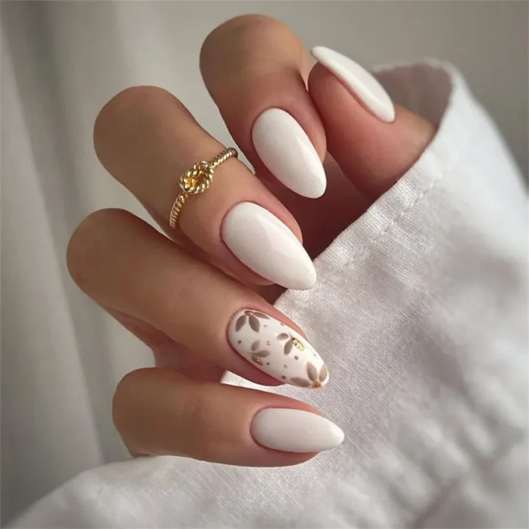 Hand with white almond nails, gold leaf design, and ring